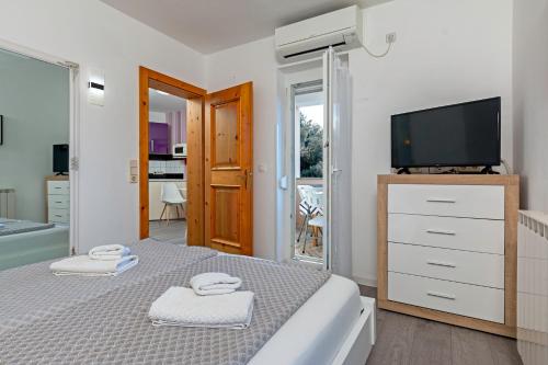 1 dormitorio con TV y 1 cama con toallas en Apartments Antic, en Pula