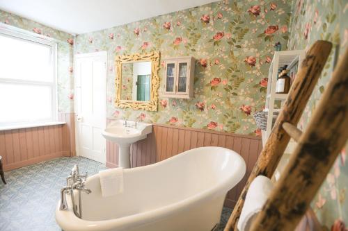 een badkamer met een bad en een wastafel met bloemenbehang bij Ferndale Cottage in Lynmouth