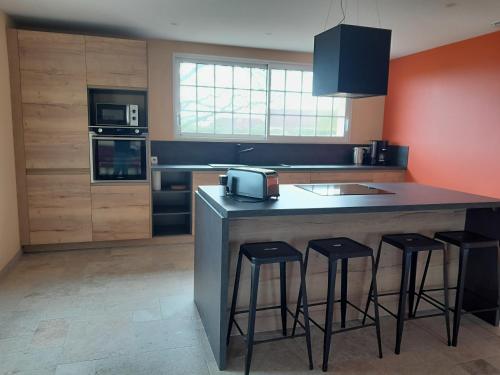 - une cuisine avec un îlot doté de tabourets de bar et d'un évier dans l'établissement Domaine Cosme, à Le Noyer-en-Ouche