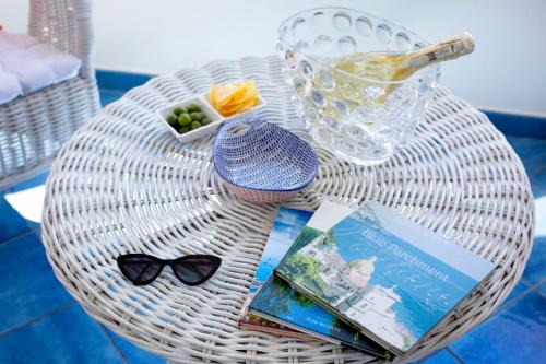 a wicker table with a book and glasses and a drink at Casa Oceano in Positano