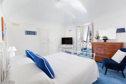 a white bedroom with a bed and a chair at Casa Oceano in Positano