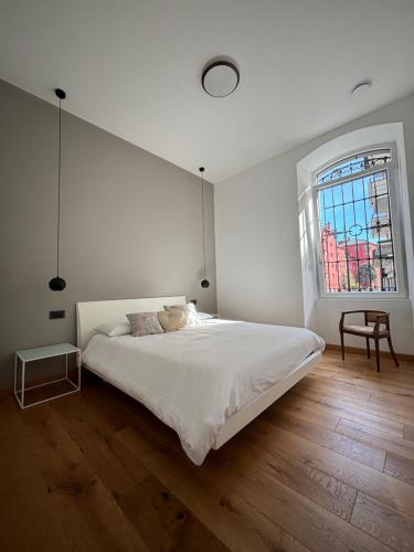 a white bedroom with a large bed and a window at Residenza la Torretta in Domodossola