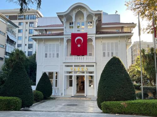 un edificio blanco con una bandera roja en él en Pool Rooftop Kadikoy Bagdat St. Seaside metro 5mins Metro, en Estambul