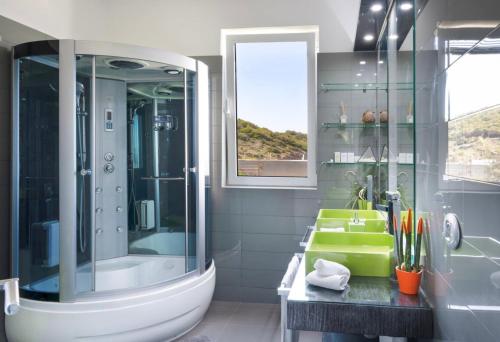 ein Bad mit einer Badewanne, einer Dusche und einem Waschbecken in der Unterkunft Villa Coral Luxury Resort in Agios Spyridon