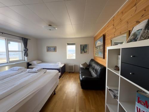 een kleine kamer met 2 bedden en een bank bij Fagrabrekka Private Room in Staður
