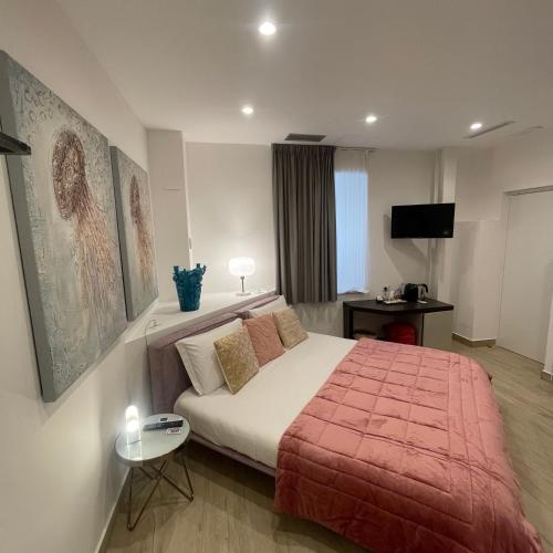 a bedroom with a bed with a red blanket and a table at Namuri Luxury Rooms in Taormina
