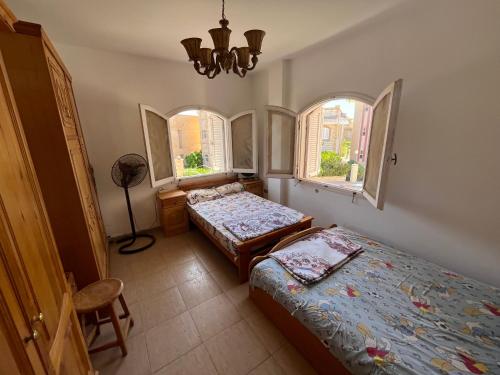 een slaapkamer met 2 bedden en 2 ramen bij Luxury Inn: 3BR Villa in North Coast Area 61 Km in Dawwār ‘Abd Allāh