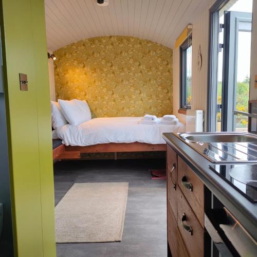 1 dormitorio con 1 cama con pared amarilla en DANÚ Shepherd's Hut, en Tralee