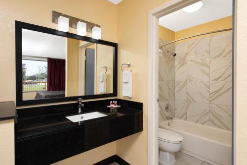 a bathroom with a sink and a toilet and a mirror at Days Inn by Wyndham Salem, IL in Salem