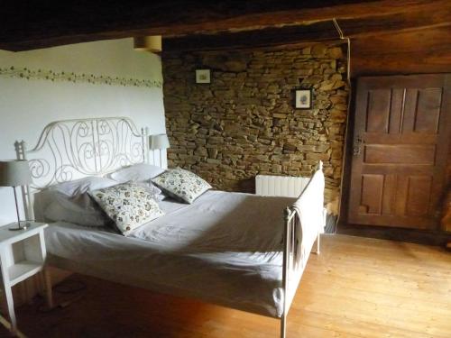 een slaapkamer met een bed en een stenen muur bij Les Hirondelles in Les Portes du Coglais
