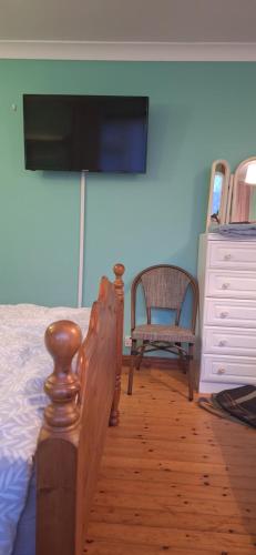 um quarto com uma cama e uma cadeira e uma televisão em Stay with Jack 2 em Ardagh