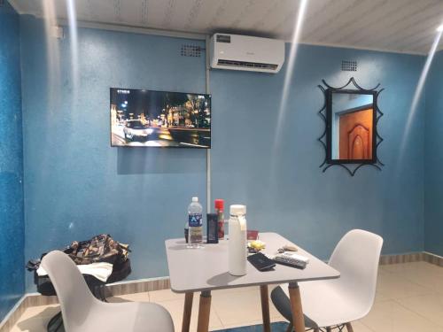Bukari Executive Lodge في Mpongwe: طاولة وكراسي في غرفة ذات جدار أزرق