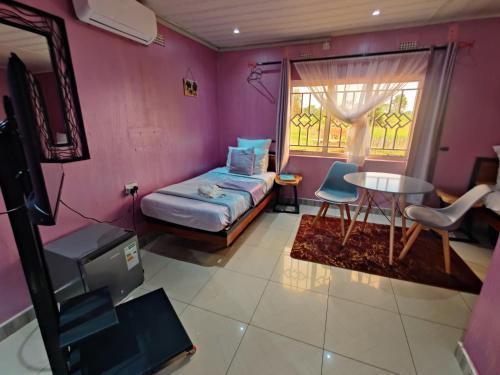 MpongweにあるBukari Executive Lodgeのベッド、テーブル、窓が備わる客室です。