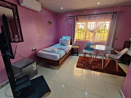 a room with a bed and a table and a window at Bukari Executive Lodge in Mpongwe