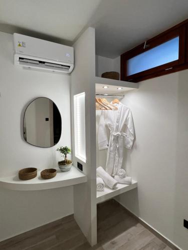 ein Badezimmer mit einem Spiegel und einem weißen Hemd auf einem Regal in der Unterkunft Olea White in Skiathos-Stadt
