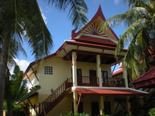 a house with a balcony and palm trees at Palm Village in Rawai Beach