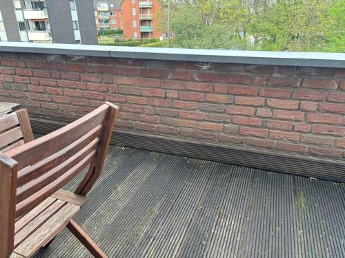 un banc en bois assis sur un balcon avec un mur en briques dans l'établissement Maisonette Wohnung in Bergheim:, à Bergheim