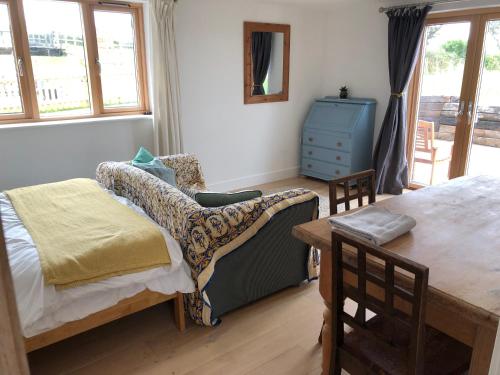 a bedroom with a bed and a table and chairs at Apple Tree Barn - converted barn with meadow views in Helston