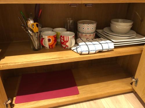 a shelf with cups and plates and utensils at Apple Tree Barn - converted barn with meadow views in Helston