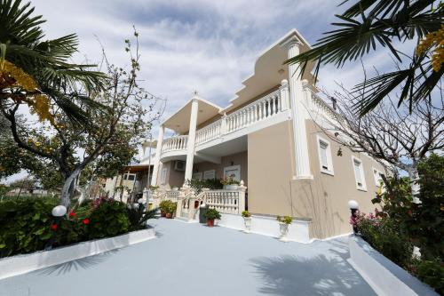 a large white house with a balcony and trees at Guest House Narta in Vlorë