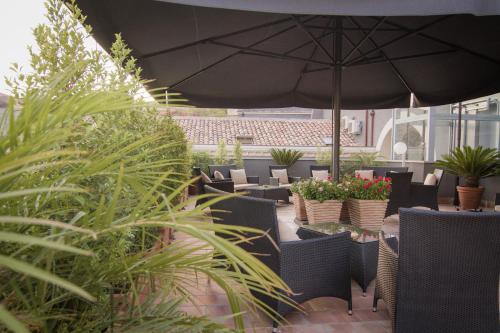a patio with chairs and an umbrella and plants at Dimora De Mauro in Catania