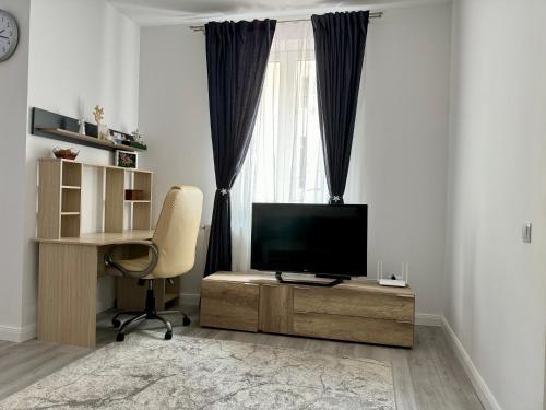 ein Wohnzimmer mit Fernseher, Sessel und Schreibtisch in der Unterkunft Ely`s Place in Sibiu