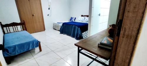 Cette chambre comprend 2 lits et une table. dans l'établissement Suítes Dona Maria de Tino, à Milho Verde
