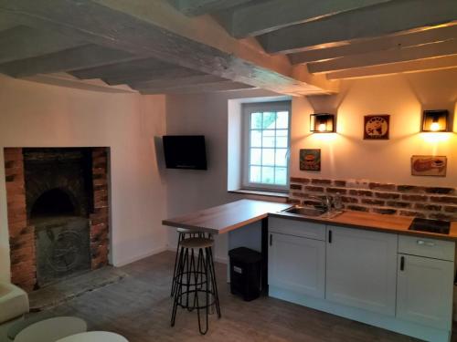 a kitchen with a counter and a fireplace at La maison du four à pain in Grandchamp