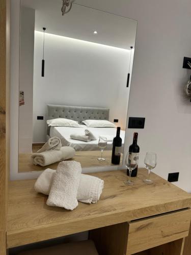Zimmer mit einem Tisch mit zwei Gläsern und einem Spiegel in der Unterkunft Suites Kozi in Sarandë