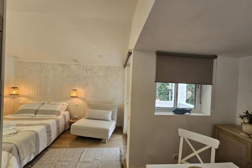 a bedroom with a bed and a chair and a window at Casa da Aldeia in Olhos de Água