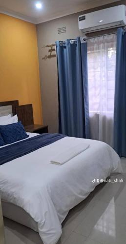 a bedroom with a bed and a window with blue curtains at 11036 in Ndola