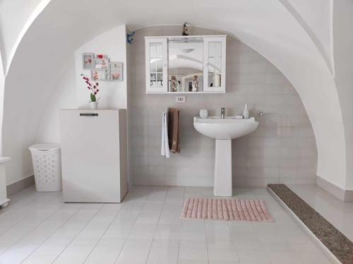een witte badkamer met een wastafel en een koelkast bij Appartamento Cuore Salento in Carmiano