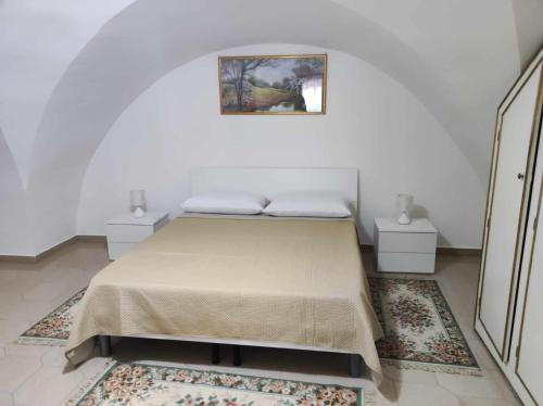 een bed in een kamer met twee tafels en een foto aan de muur bij Appartamento Cuore Salento in Carmiano