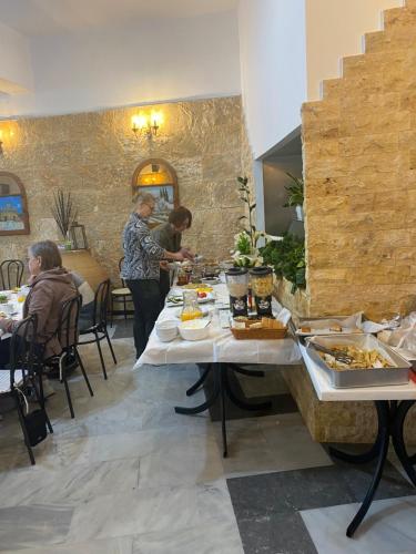 un grupo de personas de pie alrededor de una mesa con comida en Costas Inn, en Spílion