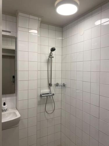 a shower in a white tiled bathroom with a sink at Korsnäsgården in Dala-Järna