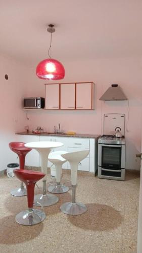 a kitchen with a white table and red chairs at La Plata 1643 in La Plata
