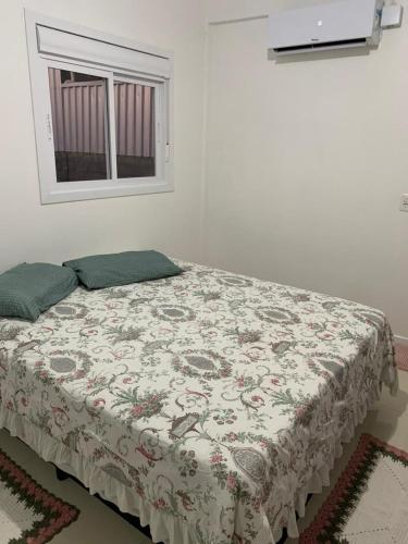 een bed in een witte kamer met een raam bij Pousada Thereza in Bento Gonçalves