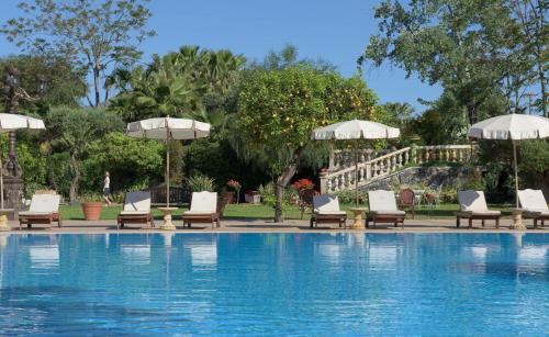 uma piscina com espreguiçadeiras e guarda-sóis ao lado de uma piscina em Castello di San Marco Charming Hotel & SPA em Calatabiano