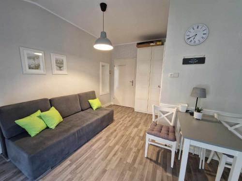 ein Wohnzimmer mit einem Sofa, einem Tisch und einer Uhr in der Unterkunft Leśny zakątek apartament nr 5 in Radzyń