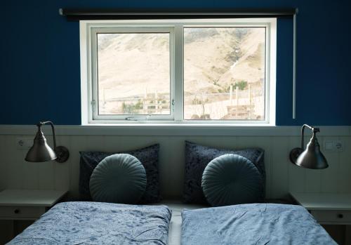 a blue bedroom with two beds and a window at Vík Hostel in Vík