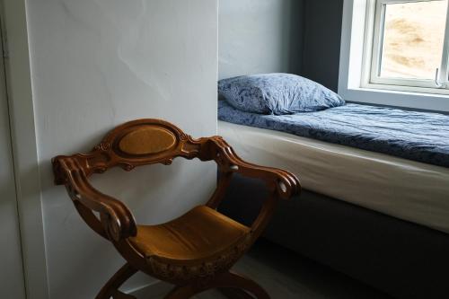 a wooden chair in a room with a window at Vík Hostel in Vík