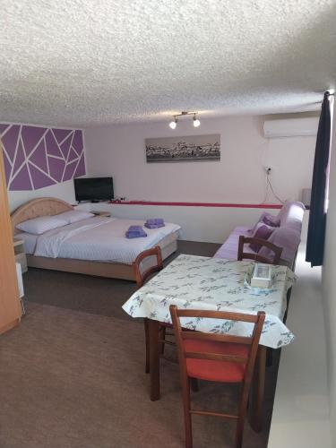 1 dormitorio con 1 cama, mesa y sillas en Petkovic Apartmani 2 en Tivat