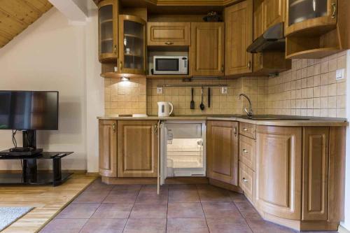 a kitchen with wooden cabinets and a sink and a microwave at Apartament Giewont in Kościelisko