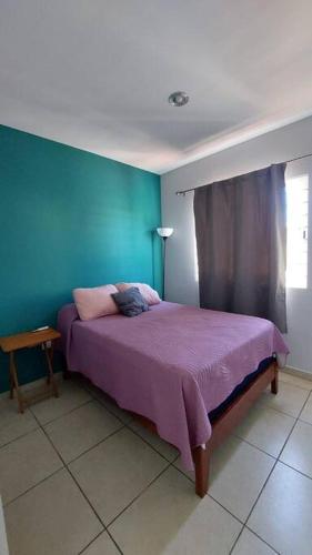 a bedroom with a purple bed and a blue wall at House 5 min by the beach, with wide open garage. in Mazatlán
