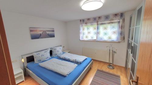 a small bedroom with a blue bed and a window at Ferienwohnung für 5 Personen in Wasserburg in Wasserburg am Bodensee