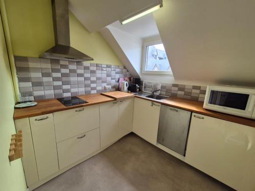 une petite cuisine avec des armoires blanches et un micro-ondes dans l'établissement Studio avec terrasse, à Bagnoles-de-l'Orne