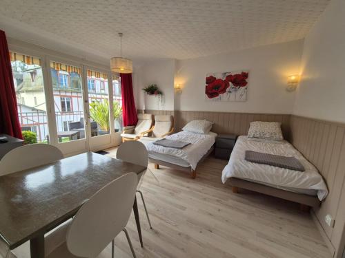 une chambre avec deux lits, une table et des chaises dans l'établissement Studio avec terrasse, à Bagnoles-de-l'Orne
