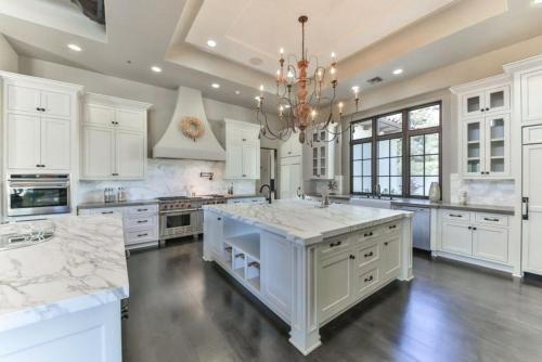 a large kitchen with white cabinets and a chandelier at Brown Villa in Edmonton