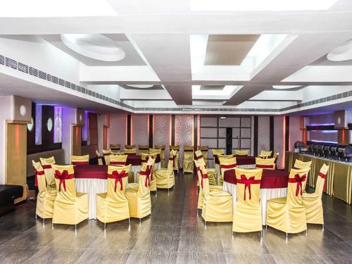 una sala banchetti con sedie gialle e tavoli con archi rossi di Vihang's Inn a Thane