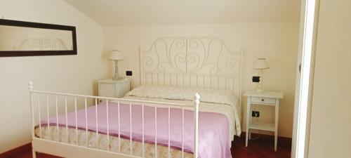 1 dormitorio con cama blanca y manta rosa en I Campi di Lino, en Finale Ligure